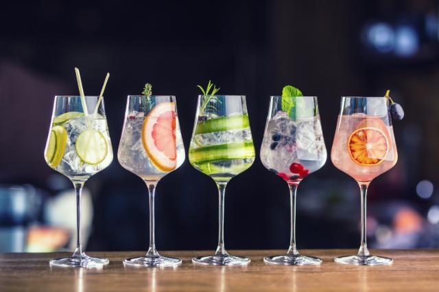 a row of glasses filled with ice and bright fruit garnishes
