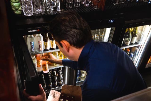 a bartender removes a bottle from an MG3 cabinet