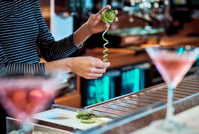 a bartender prepares a cocktail with a brightly illuminated Gamko counter in the background