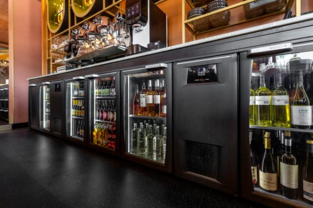 An attractive display of wine and beer bottles in a Flexbar shown within a stunning bar location.